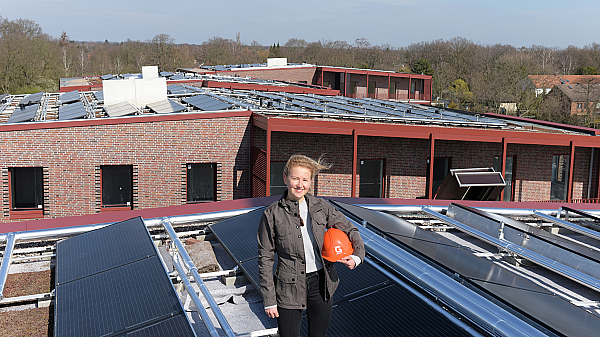 Gundlach-Mitarbeiter Sophie Jürges neben den Solarthermie-Installationen auf den Gebäuden im Herzkamp.